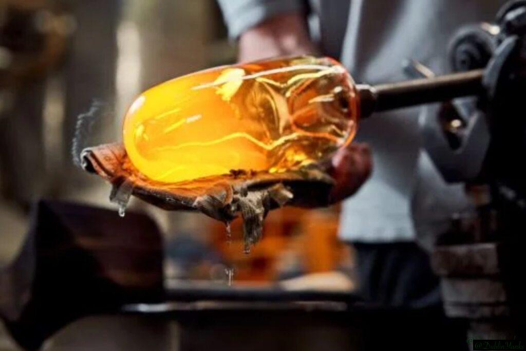 Glassblower shaping molten glass on a rod in a workshop